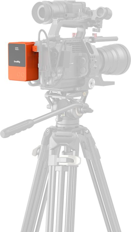 Orange V-mount battery mounted on tripod camera rig, LCD showing 100%