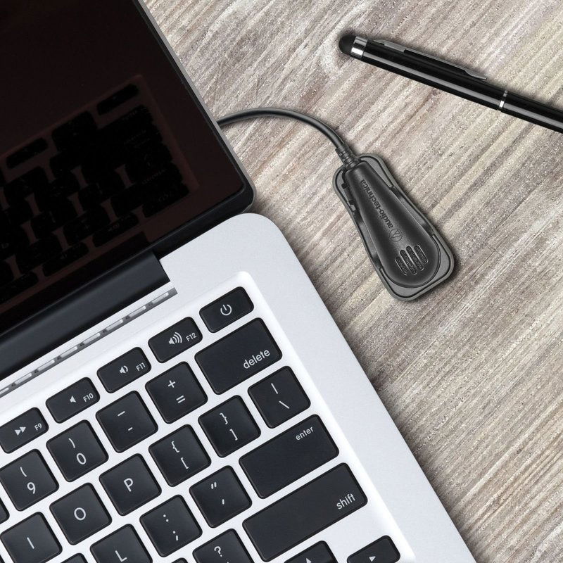 Black USB microphone resting on desk with connected cable