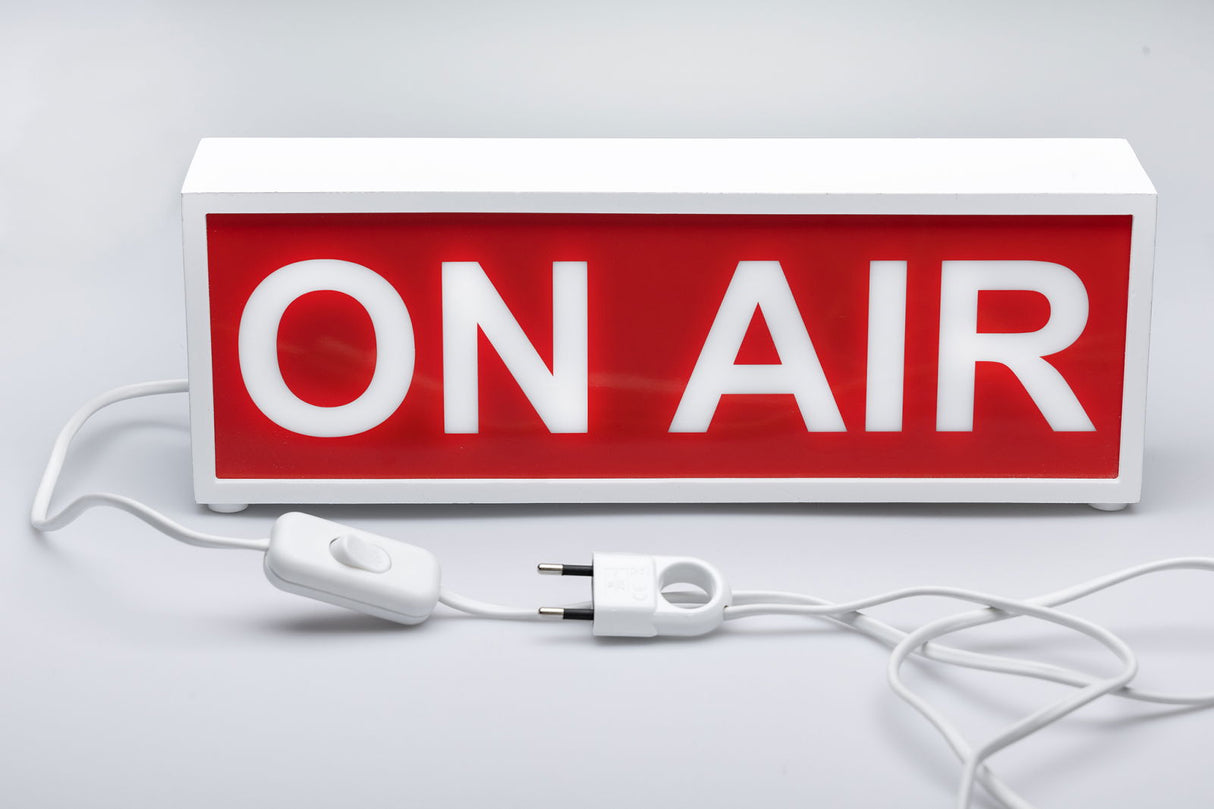 ON AIR light box sign with white letters on red panel, white casing with power cord and plug.