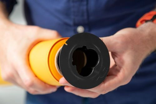 Hands holding black background brake/clamp around orange backdrop roll