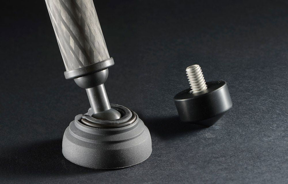 Tripod base close-up: rubber foot and leveling knob on carbon-fiber leg, black