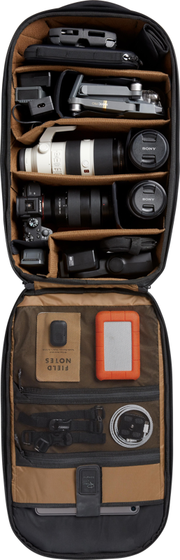 Open black camera backpack with foam compartments holding DSLR and lenses