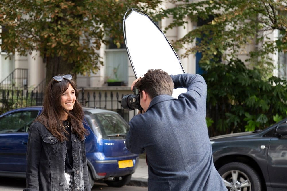 Circular diffusion reflector held above camera outdoors, white fabric facing lens