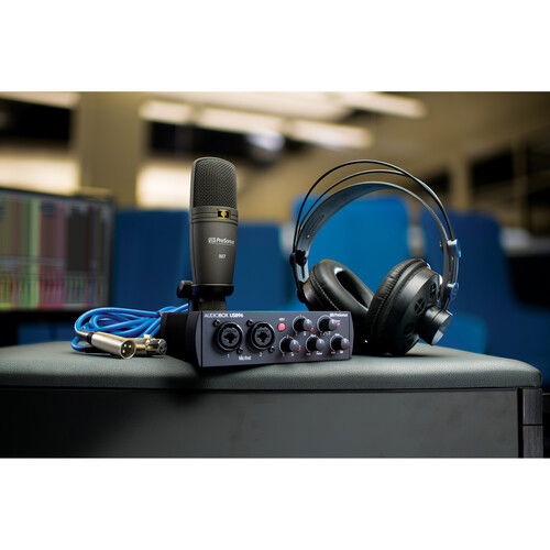 Condenser mic, audio interface with knobs, headphones on tabletop
