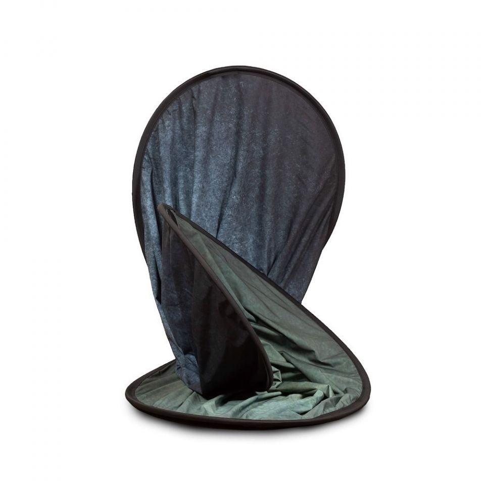 Folded portable backdrop with dark outer fabric and sage-green inner side