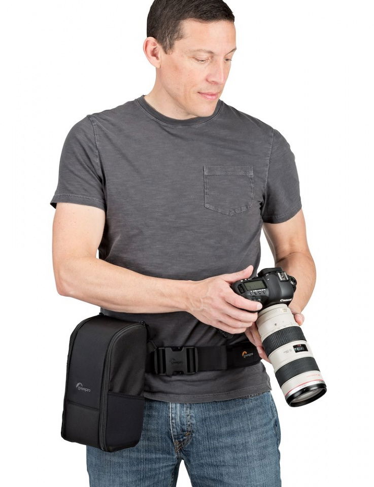 Black camera bag with shoulder strap; person carries compact lens and camera