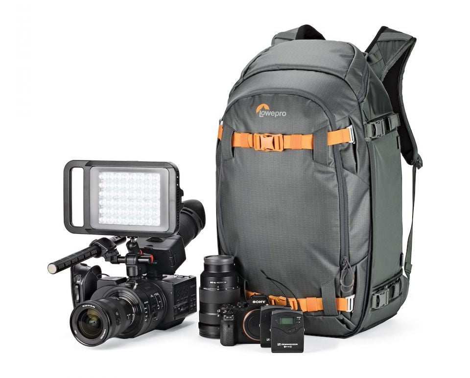 Gray camera backpack with orange straps beside camera body, lens, and accessories