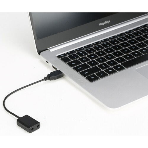 Adaptor audio Jack 3,5 la USB 2.0, mufă compactă și cablu, lângă laptop.