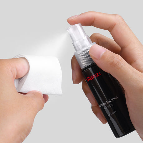 Sticlă neagră cu spray și lavetă albă pentru curățarea lentilelor
