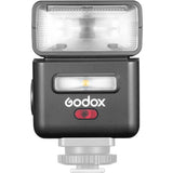 Mini TTL speedlite with open flash head and glowing LED window, dark body