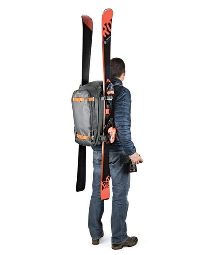 Gray backpack side view on person, orange straps and adjustable shoulder harness visible