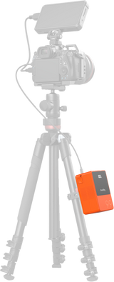 Orange V-mount battery on tripod camera setup with LCD showing 100% and cables