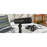 Microfon USB dinamic hipercardioid negru pe stativ, lângă căști