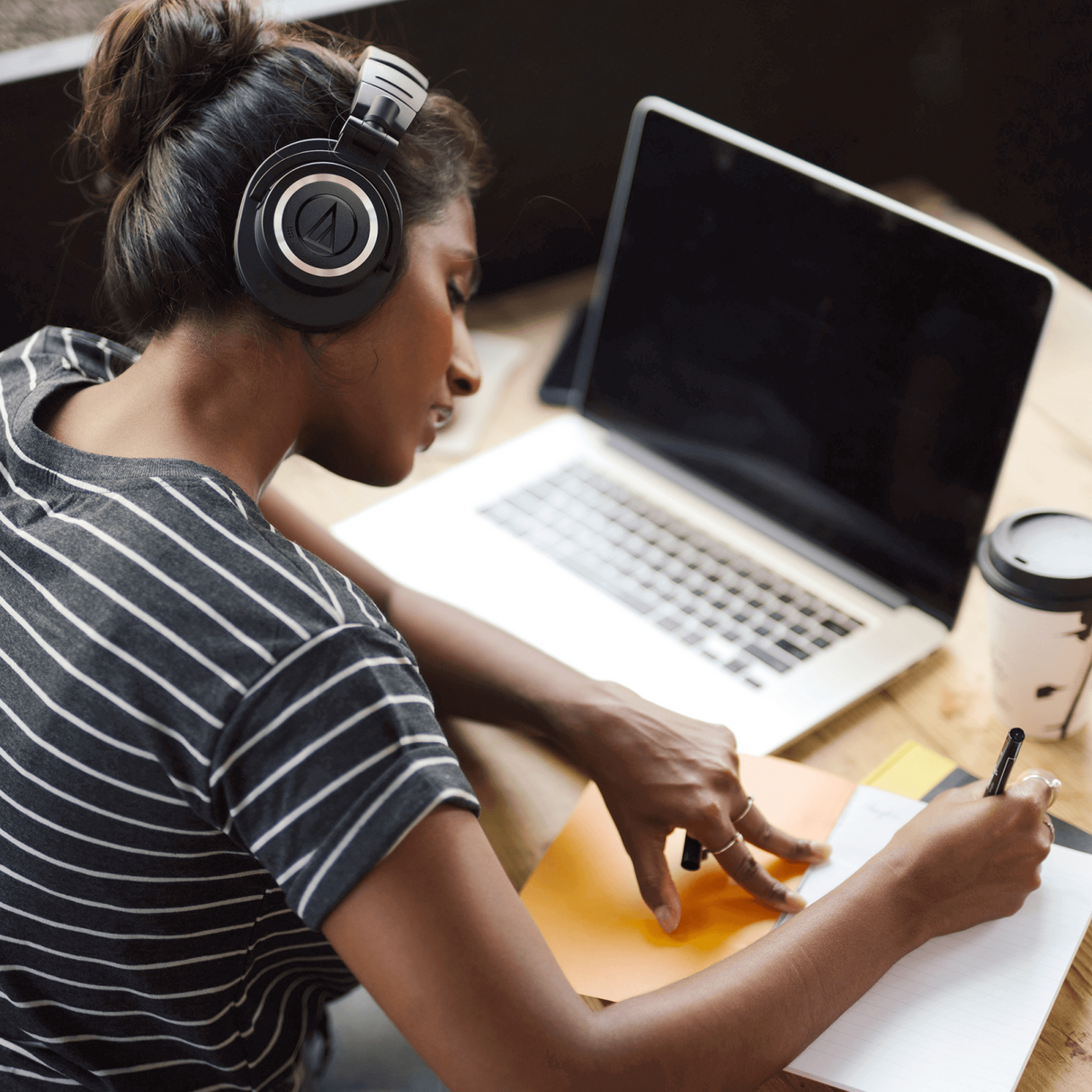 Person wearing black over-ear Bluetooth headphones for listening