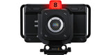 Black studio camera with front lens, top red tally, rig handles, compact body