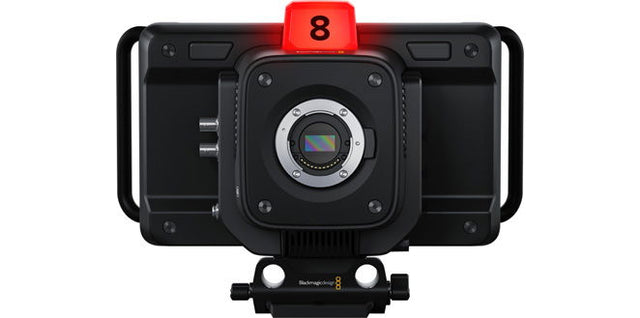Black studio camera with front lens, top red tally, rig handles, compact body