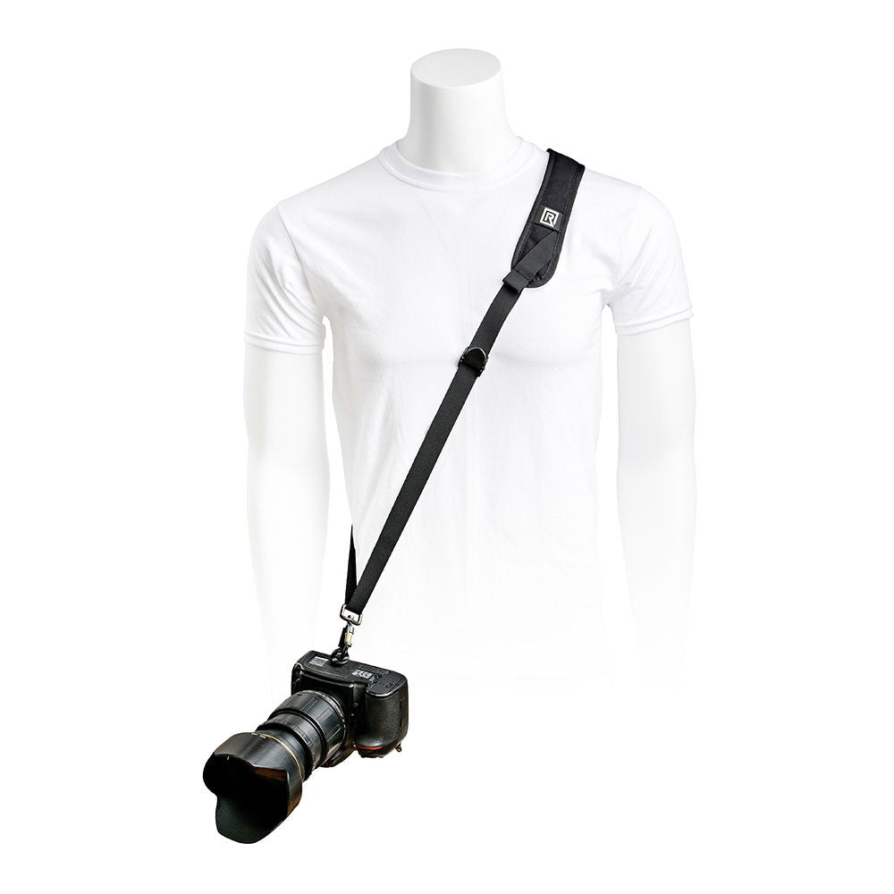 Black camera strap worn diagonally over a white shirt; adjustable buckle