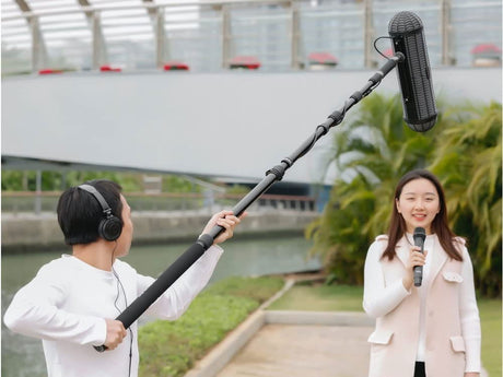 Telescopic carbon-fiber boom pole holding a microphone with foam windscreen