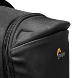Close-up of gray backpack fabric, front corner seam, and orange logo patch