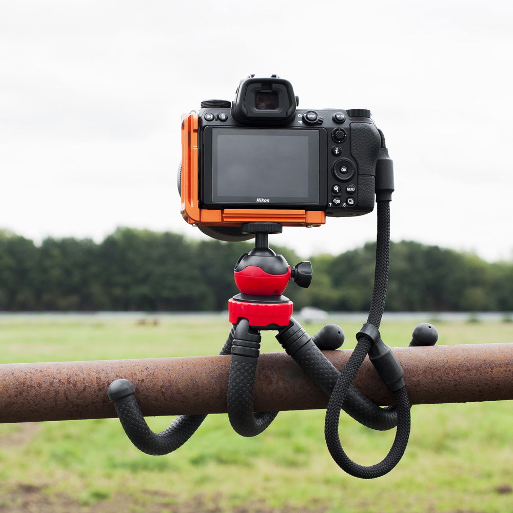 Mini tripod on ball head with camera attached; textured black legs and grips