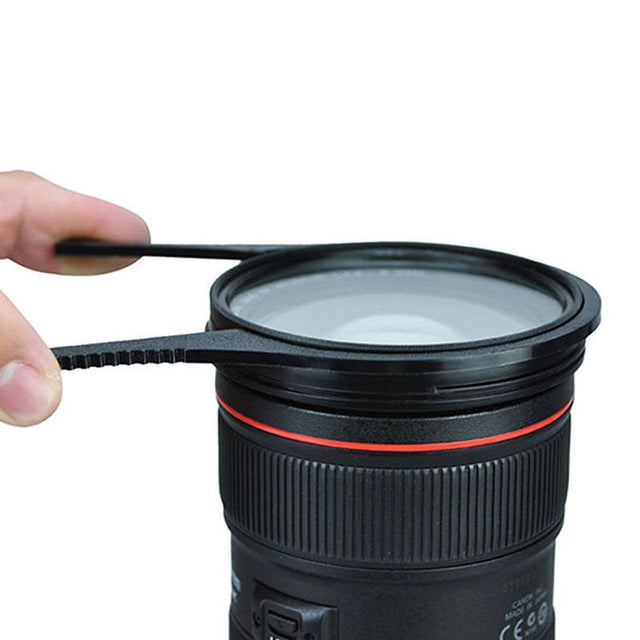 Black filter unlocking tool ring with red band; hand holds it above a lens