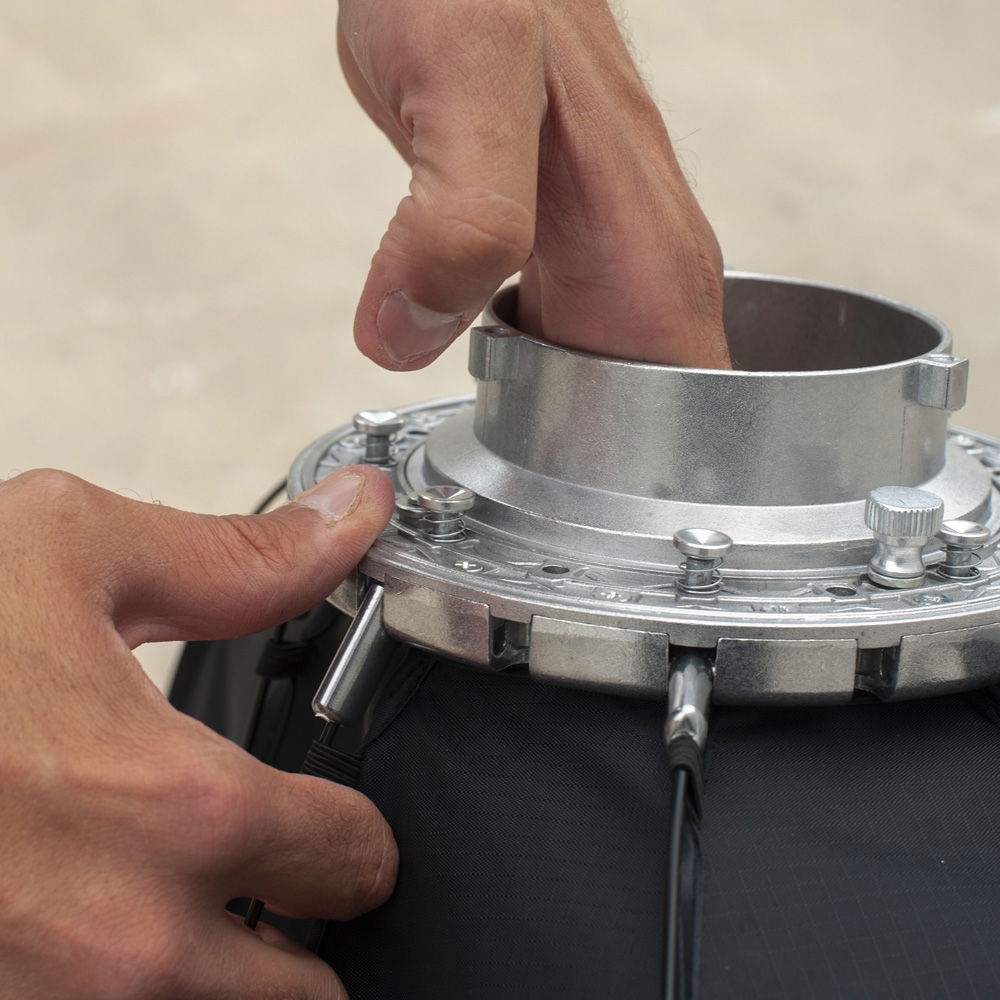 Hands attaching Bowens-mount ring to octagonal softbox frame quick-assembly hardware