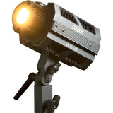 Warm-lit bi-color LED spotlight on tripod mount, glowing front reflector