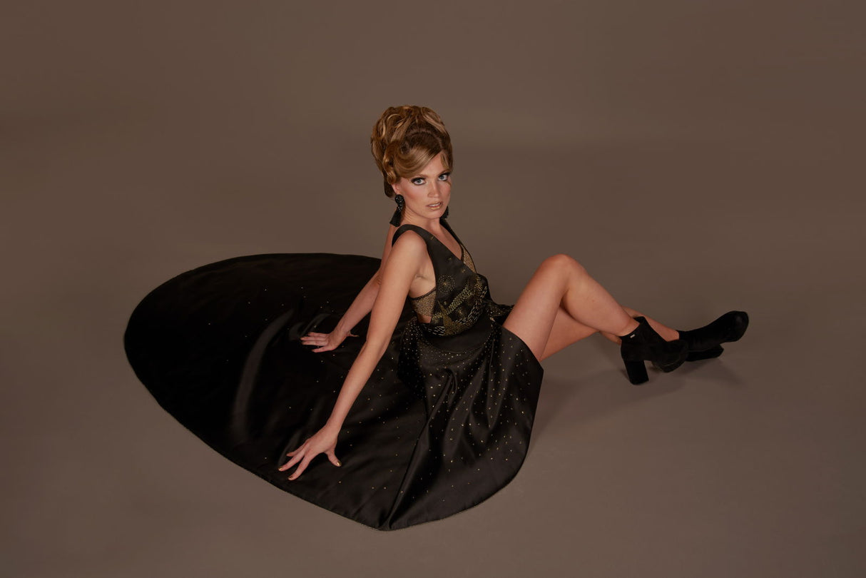 Photo backdrop sheet in studio, with model posing in a black dress