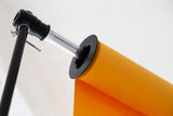 Orange backdrop roll with black circular clamp on stand arm