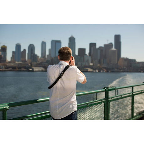 Camera strap on person’s back with shoulder strap and buckle detail