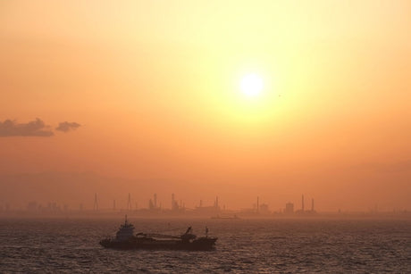 Sunset over water with ships in the distance and warm orange sky