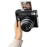 Hand holding Instax SQ40 instant camera with photo showing two people