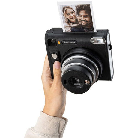 Hand holding Instax SQ40 instant camera with photo showing two people