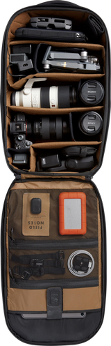Open black camera backpack with foam compartments holding DSLR and lenses