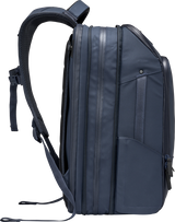 Navy travel backpack angled side view with multiple vertical side seams and strap