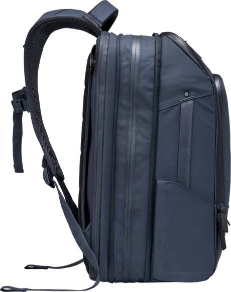 Navy travel backpack angled side view with multiple vertical side seams and strap