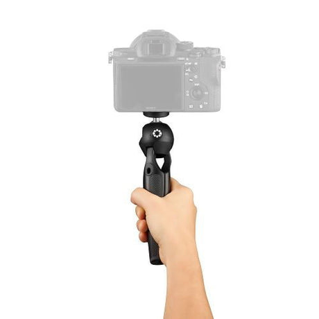 Mini tripod held in hand, black base with camera mounted on top