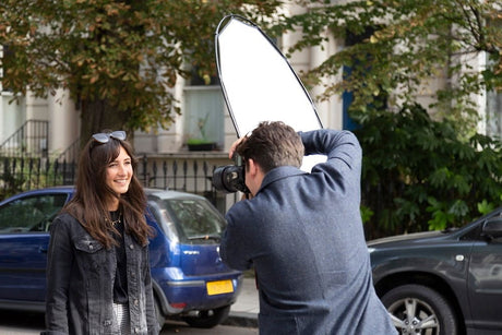 Circular diffusion reflector held above camera outdoors, white fabric facing lens