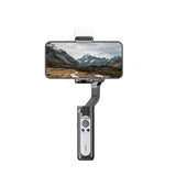Smartphone stabilizer gimbal with magnetic LED light on clamp, dark gray/black body