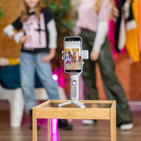 Mini tripod-mounted smartphone stabilizer with LED light and phone clamp on table