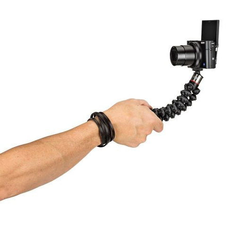 Hand holding black flexible mini tripod with camera mounted on bendable legs