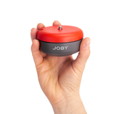 Suport telefon Joby 360 panoramic, carcasă roșie și bază neagră, ținut în mână
