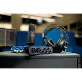 Condenser mic, audio interface with knobs, headphones on tabletop