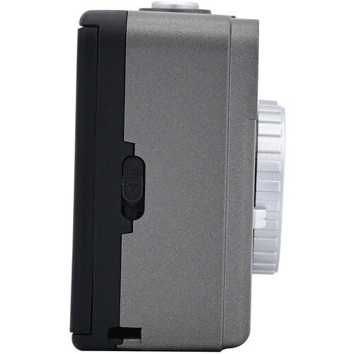 Side of half-frame film camera with textured panel and ridged white film compartment dial