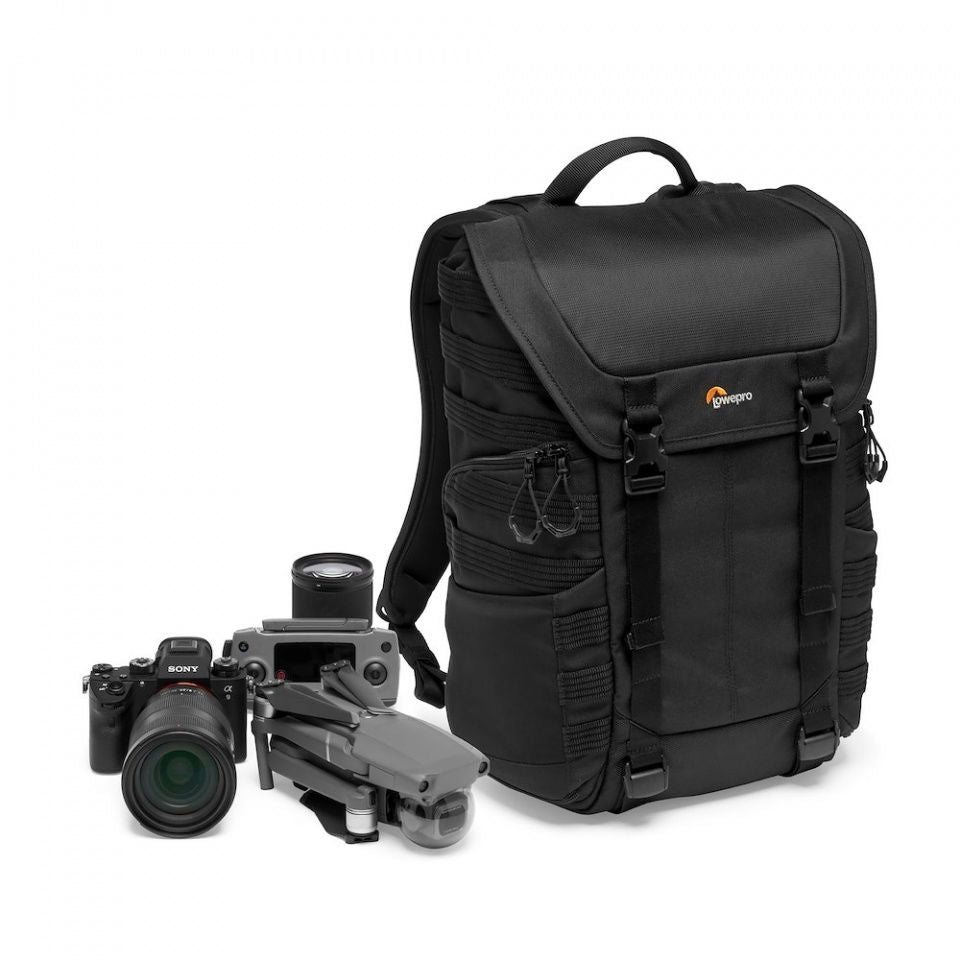 Black camera backpack with front flap, shown with camera and lens accessories nearby