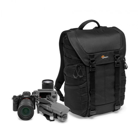 Black camera backpack with front flap, shown with camera and lens accessories nearby