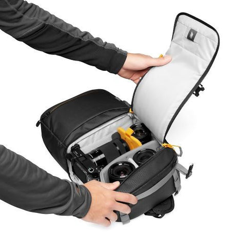 Open black camera backpack with white interior and compartments for camera and lens