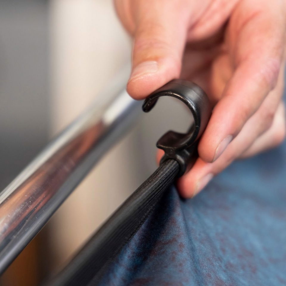 Hand clips a black frame rail to ink blue backdrop fabric