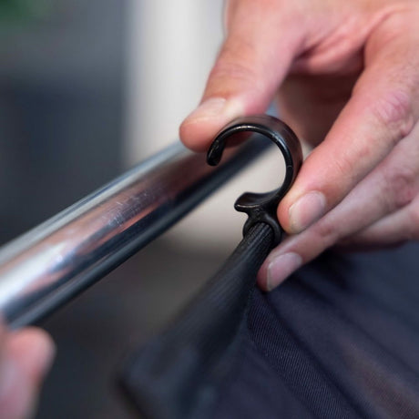 Hand fastening the backdrop fabric to the frame with a strap clamp