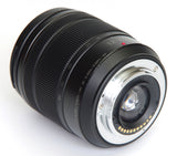 Angled close-up of black 12-60mm camera lens front glass and mounting ring